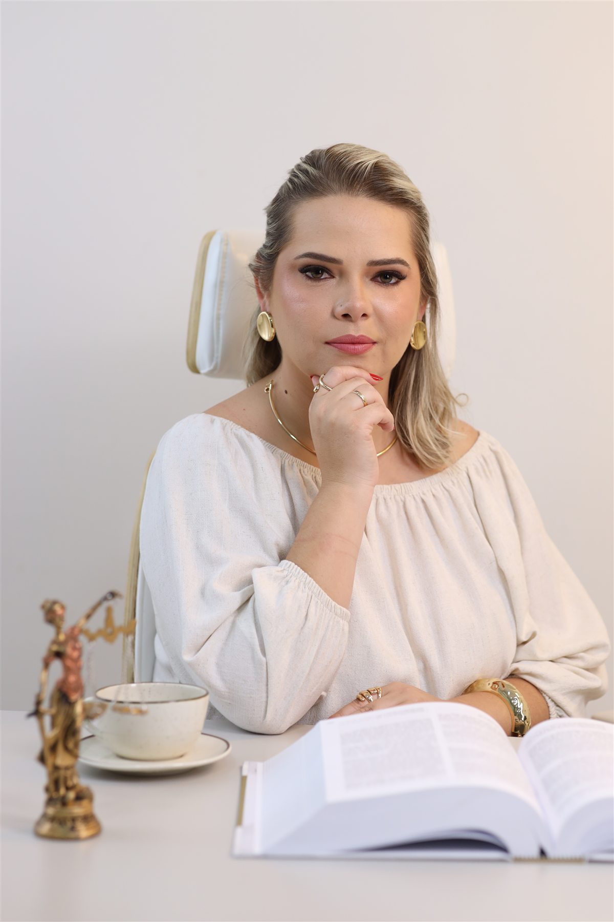 Dra. Leticia Oliveira em seu escritório, ao lado de livros jurídicos